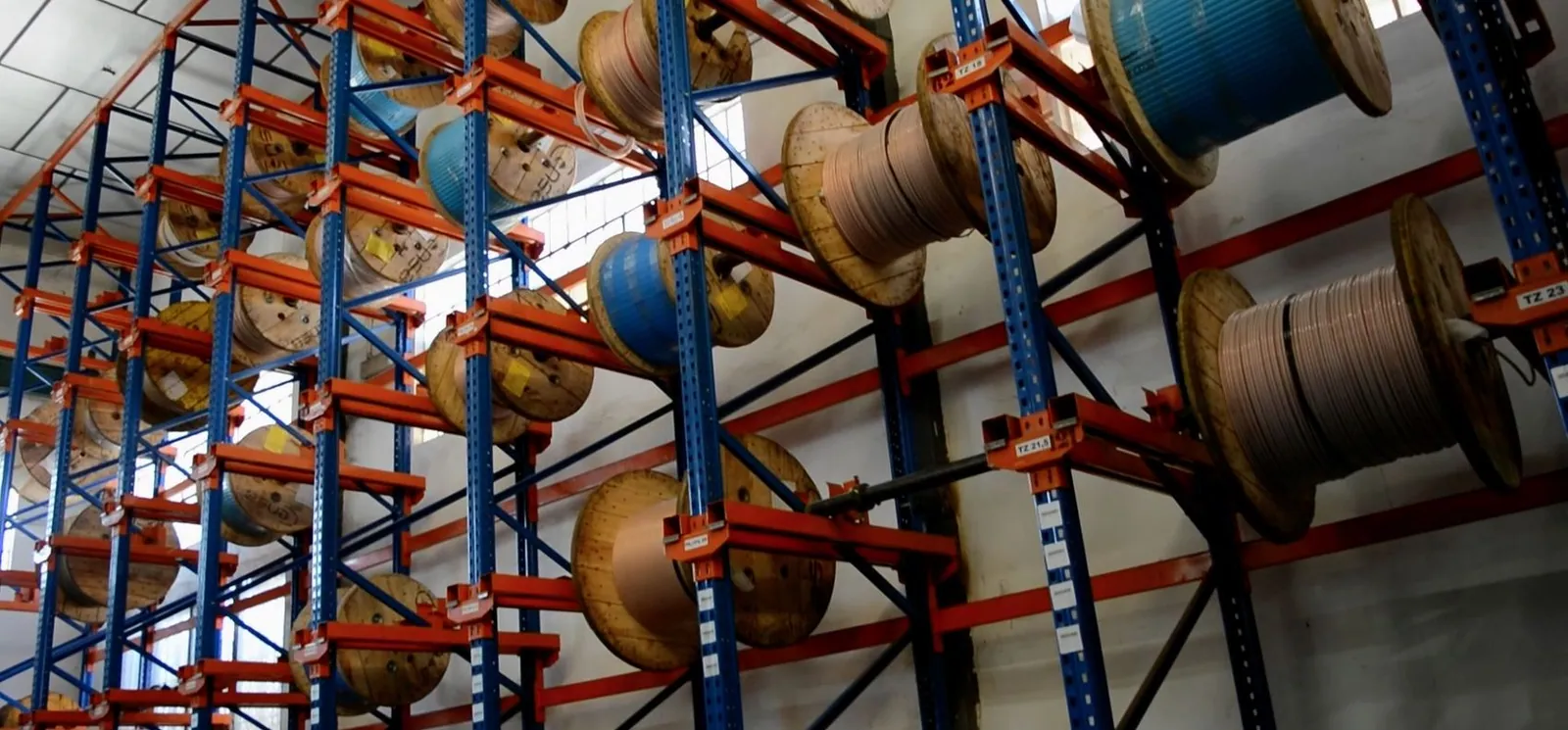 Estanterías del almacén con carretes de cable de bobinado clasificados por sección