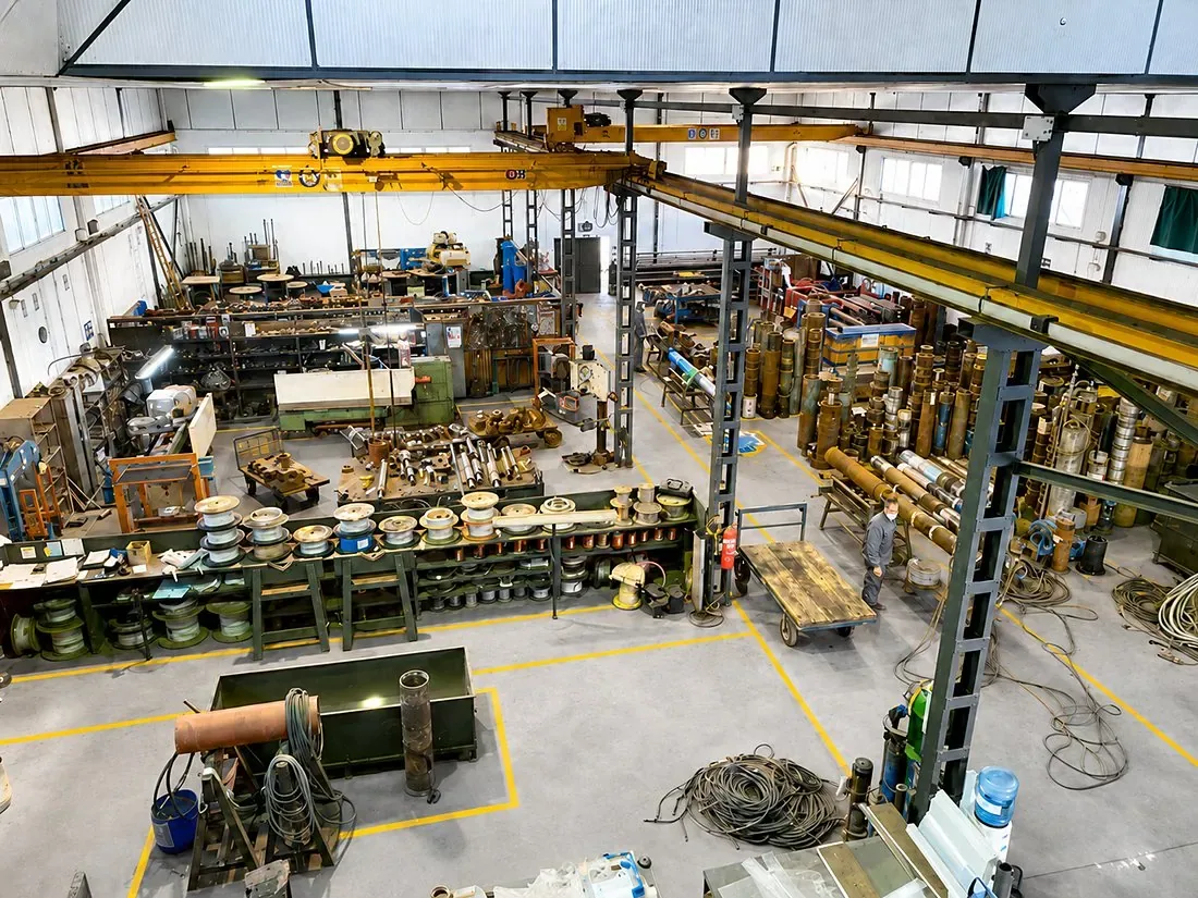 Interior de la nave del taller de Almería, con los puentes grúa, los bobineros y las bombas de pozo almacenadas