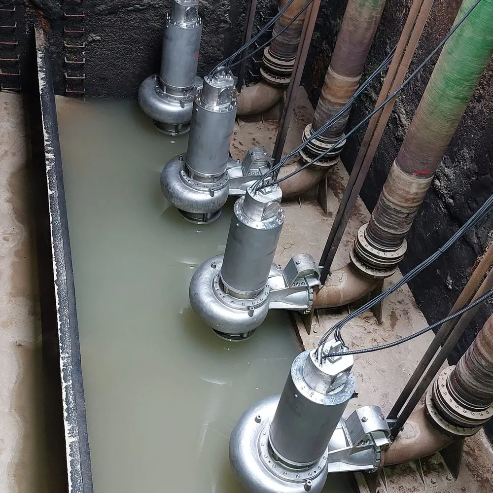 Batería de bombas sumergibles de acero inoxidable instaladas en una cámara húmeda, con la impulsión de cada grupo acometiendo al colector