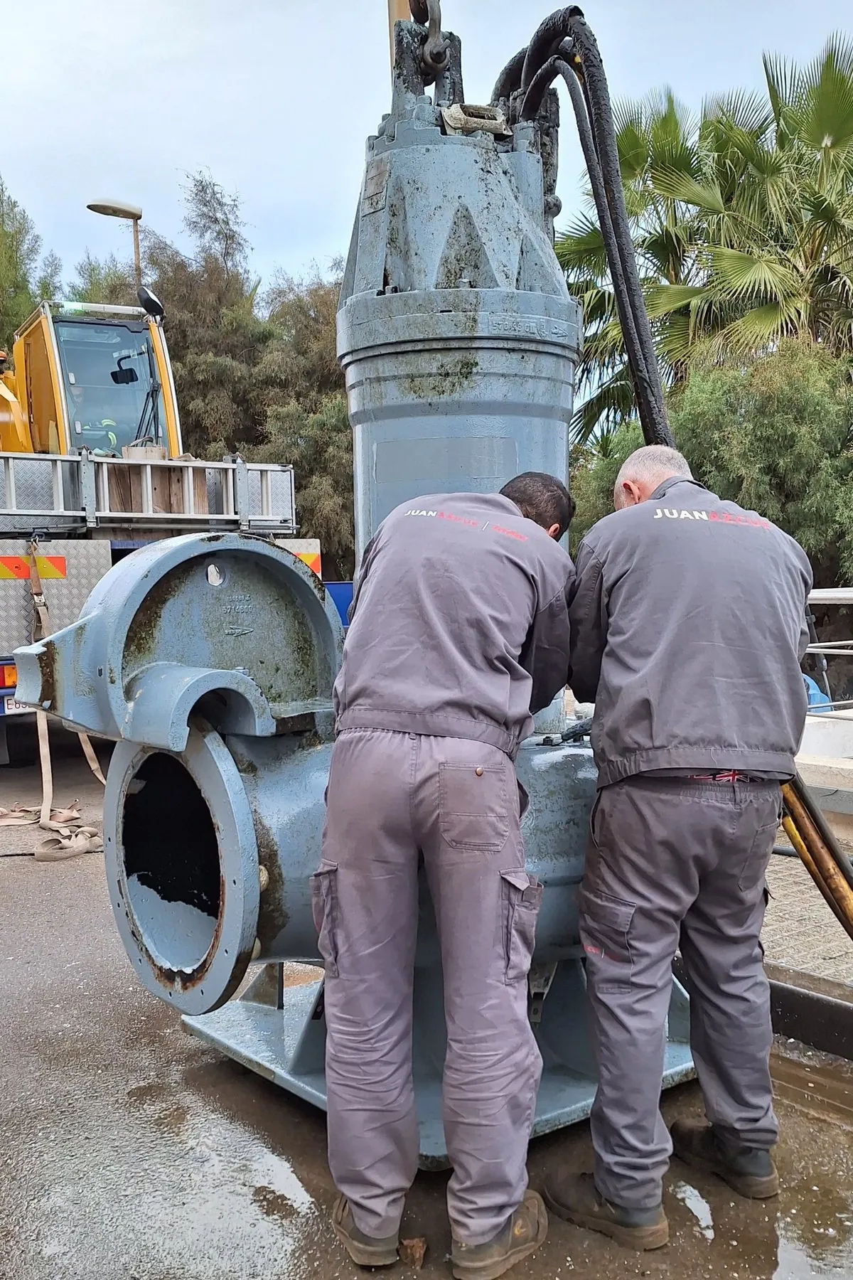 Dos operarios de Juan Azcue interviniendo sobre una bomba sumergible de gran tamaño extraída de su pozo de aspiración en una planta desaladora